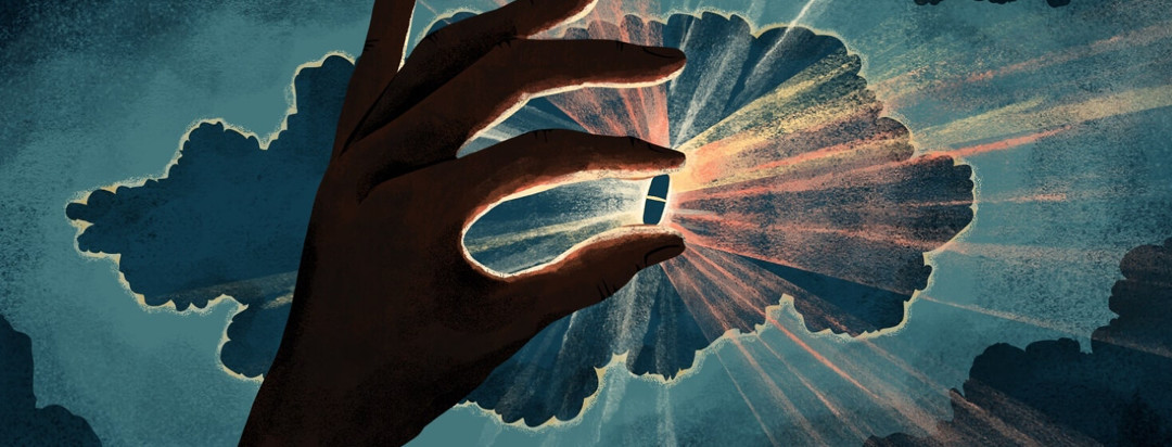 A hand in shadow holds up a pill that is illuminated from behind, emitting rays of light